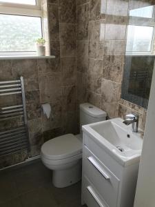a bathroom with a toilet and a sink and a window at Sea Shells in Greatstone
