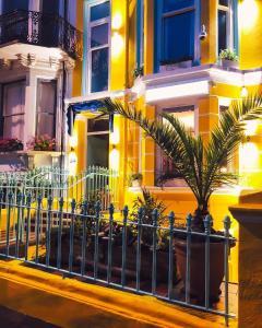 a fence in front of a yellow building with a plant at Cavalaire Guest House in Brighton & Hove