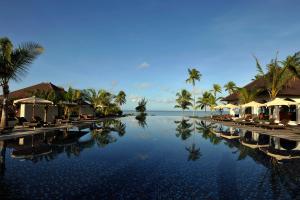 a swimming pool at a resort with palm trees and water at The Residence Zanzibar in Kizimkazi