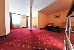 a living room with a red carpet and a couch at Hotel Magic GT Trivale in Piteşti