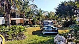 een oude auto geparkeerd in een tuin met palmbomen bij Bali Hai Beachfront Resort and Spa in Holmes Beach