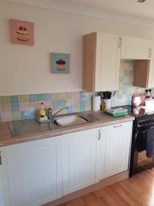 a kitchen with white cabinets and a sink at Binfield Annexe in Bracknell