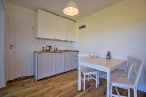 a kitchen with white cabinets and a table and chairs at Cztery Domki in Stare Kiejkuty