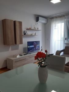een woonkamer met een vaas met een bloem op een tafel bij Elena apartmani in Tuzla