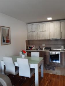 een keuken met een witte tafel en witte stoelen bij Elena apartmani in Tuzla