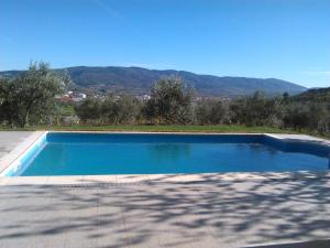 una piscina azul con montañas en el fondo en Casa das Argolas en Macedo de Cavaleiros