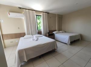 a hotel room with two beds and a window at Pousada Vila do Porto in Porto De Galinhas