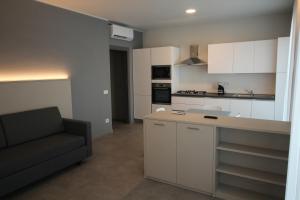 uma cozinha com armários brancos e um sofá num quarto em Persea mare appartamenti em Arma di Taggia