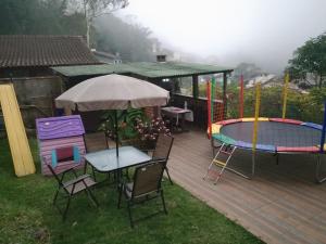 a deck with a table and chairs and a tennis court at Casa Petrópolis Temporada in Petrópolis