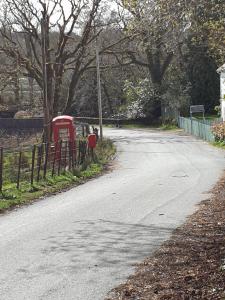 una calle con una cabina telefónica roja al lado de una carretera en Cladich House Bed & Breakfast en Cladich