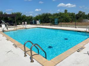 uma grande piscina azul com uma cerca de metal em La Quinta by Wyndham Ada em Ada