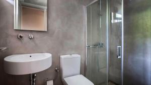 a bathroom with a toilet and a sink and a shower at Beachfront Suites Lourdas in Lourdata