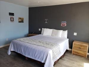 1 dormitorio con 1 cama grande y pared gris en Deluxe Inn, en Seligman