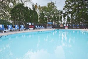 une grande piscine avec des chaises bleues et une table dans l'établissement Holiday Inn Express Detroit-Warren/General Motors Technology Center, an IHG Hotel, à Warren