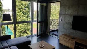 a living room with a couch and large windows at Apartament Marzenie 14 - Opole in Opole