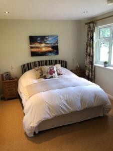 a bedroom with a large bed with white sheets at Field's Edge in Swinderby