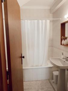 y baño con cortina de ducha y lavamanos. en Casa dos Pinheiros en São Pedro de Moel