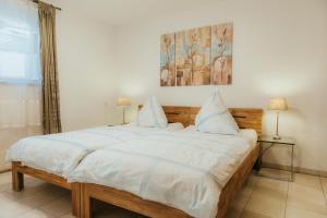 a bedroom with a large bed with white sheets at Ferienwohnung "Köhler" am Bodensee in Meckenbeuren