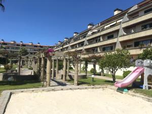 un parque infantil frente a un edificio con tobogán en Beachside Feel Full Apartment Beach & Casino en São Félix da Marinha