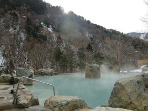 a pool of blue water with large rocks at Guest House Kura in Suzaka