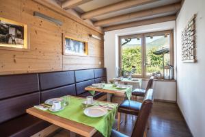 トレントにあるAgriturismo Al Manieroの窓のあるレストラン(テーブル2台、椅子付)