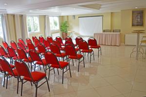 Sky Ville Hotel Canela في كانيلا: قاعة المؤتمرات ذات الكراسي الحمراء والشاشة البيضاء
