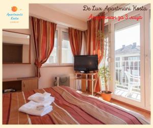 a bedroom with a bed and a tv and a window at De Lux Apartments Kosta in Ohrid