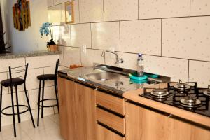 a kitchen with a sink and a stove with stools at Apart ZSS in Penha