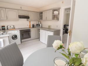 a kitchen with white cabinets and a table with a vase of flowers at Castle View in Conwy +24 photos