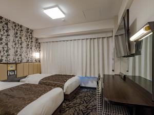 APA Hotel Nagoya Ekimae Kita في ناغويا: غرفة فندقية بسريرين وتلفزيون بشاشة مسطحة