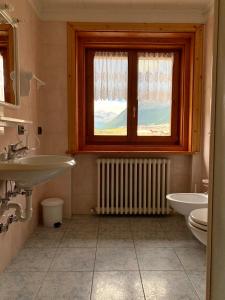 łazienka z umywalką, toaletą i oknem w obiekcie Casa Susanna w Livigno