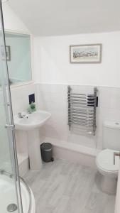 ein weißes Bad mit einem Waschbecken und einem WC in der Unterkunft Snowdon Retreat Villa by Seaside Llandudno in Llandudno