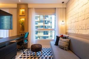 a living room with a couch and a desk and a window at Luxuoso Apto Em Frente Ao Shopping Curitiba - Piscina, Academia e Sauna in Curitiba