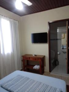 um quarto com uma cama, um chuveiro e uma televisão em Pousada Jolly Roger em Bertioga