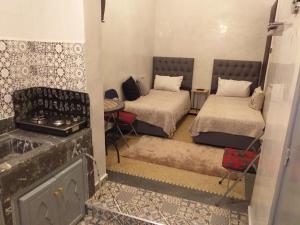 Cette petite chambre comprend 2 lits et une cuisinière. dans l'établissement studio Dar Rmila, à Marrakech