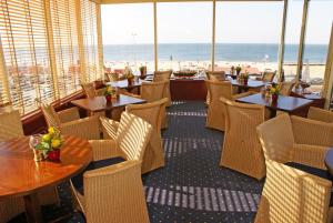 een restaurant met tafels en stoelen en uitzicht op het strand bij Boulevard Hotel Scheveningen in Scheveningen
