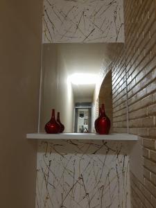 three red vases sitting on a shelf in a bathroom at HOTEL CASTELINHO DE SOROCABA in Sorocaba