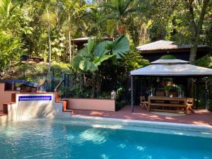 a swimming pool with a table and a gazebo at Cairns Rainforest Retreat in Cairns