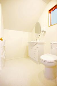 a white bathroom with a toilet and a sink at Cranbury Court Apartments in Queenstown