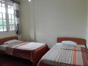 two beds in a room with a window at Keshiya Holiday Home in Nuwara Eliya