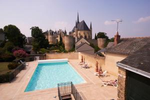 a swimming pool with a castle in the background at Hotel Spa Le Relais Du Bellay in Montreuil-Bellay