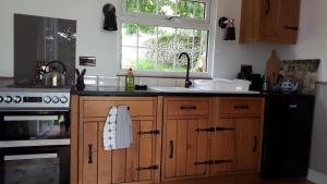 a kitchen with wooden cabinets and a sink and a window at The Owl Hoot in Ipstones