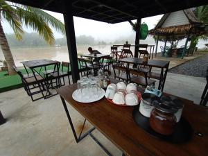 a wooden table with dishes on it with tables and chairs at Baantia Chomtawan in Surat Thani