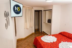 Ns Hotel في ترماس دي ريو هوندو: غرفة نوم بسرير احمر وعلامة على الحائط