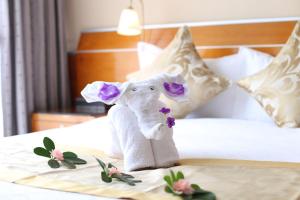 a stuffed elephant on a bed in a hotel room at Yihe Hotel Ouzhuang in Guangzhou