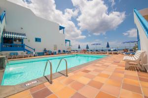 a pool at a resort with chairs and umbrellas at Apartamentos Agua Marina in Puerto del Carmen +24 photos