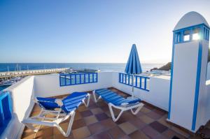a balcony with two chairs and a lighthouse at Apartamentos Agua Marina in Puerto del Carmen