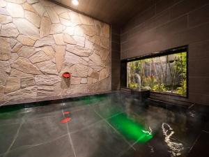 a swimming pool in a room with a stone wall at Super Hotel Iyo Saijo in Saijo