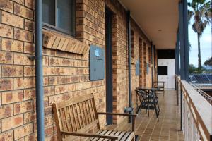 a brick building with benches and tables on a porch at Bridge View Motel in Gorokan