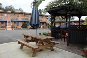 a picnic table with chairs and umbrellas in front of a building at Bridge View Motel in Gorokan